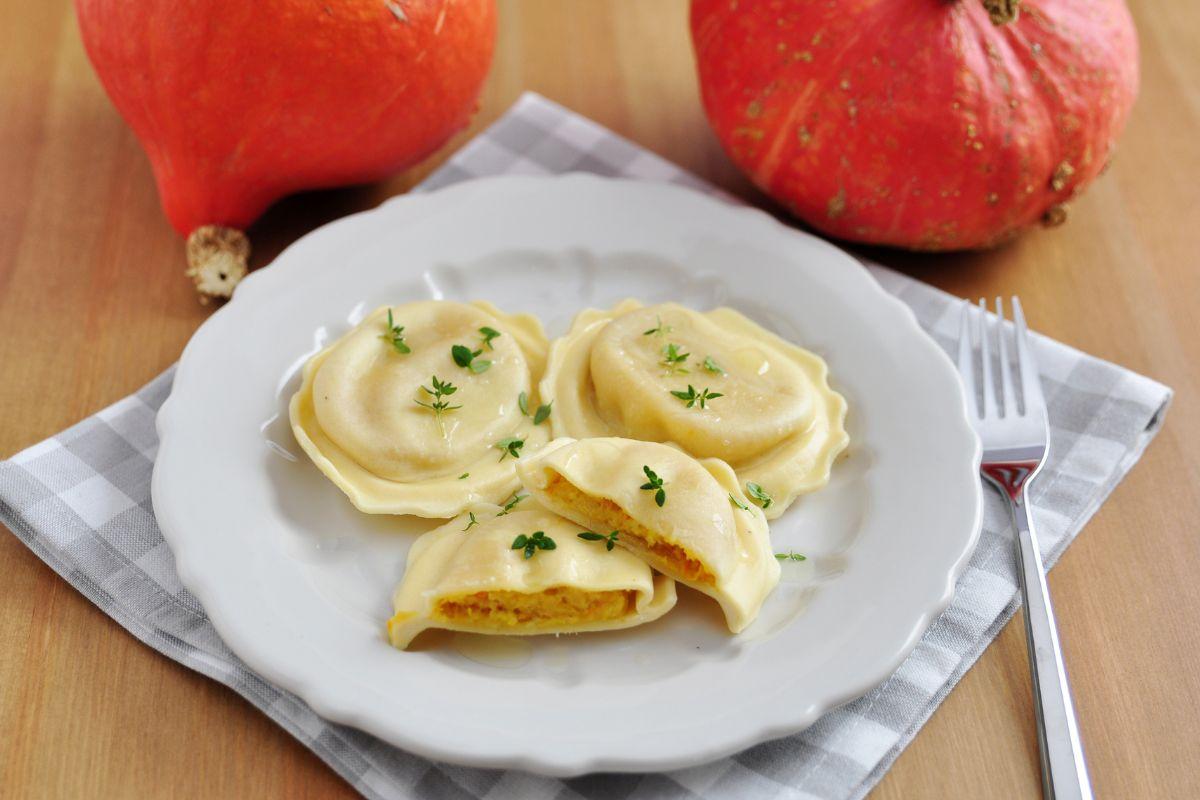 Alcuni ravioli conditi con erbe su un piatto bianco