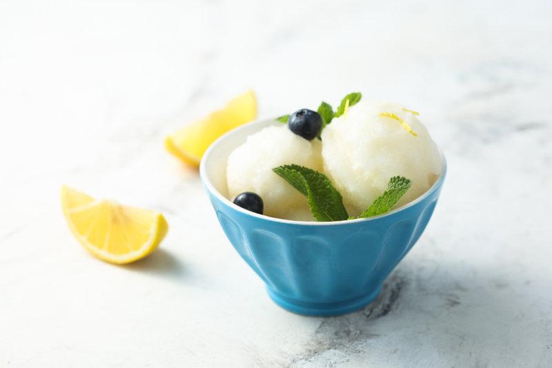 Sorbetto al limone dalla texture classica, decorato con mirtilli e foglie di menta.jpg